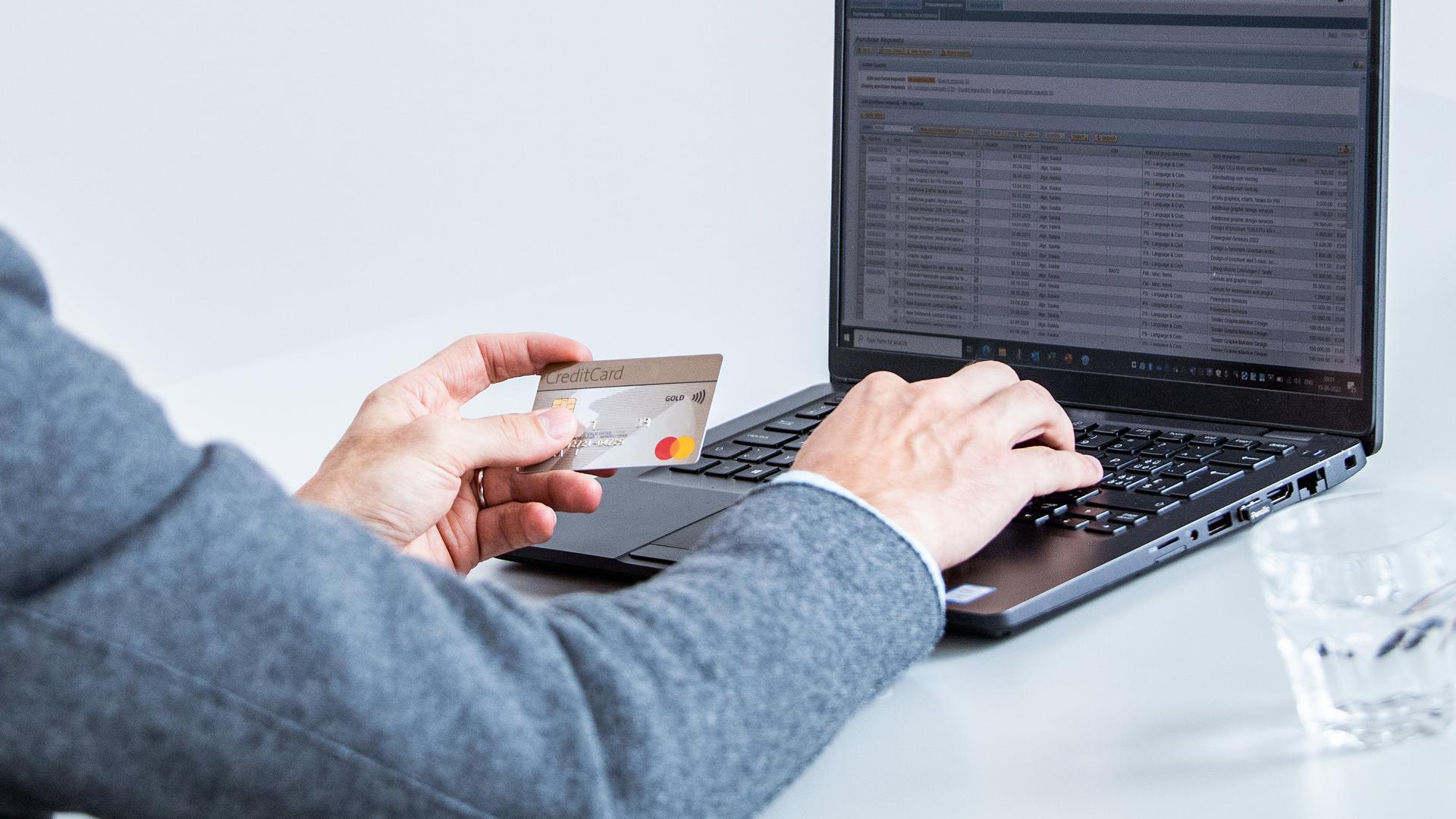 User with credit card in hand at a laptop